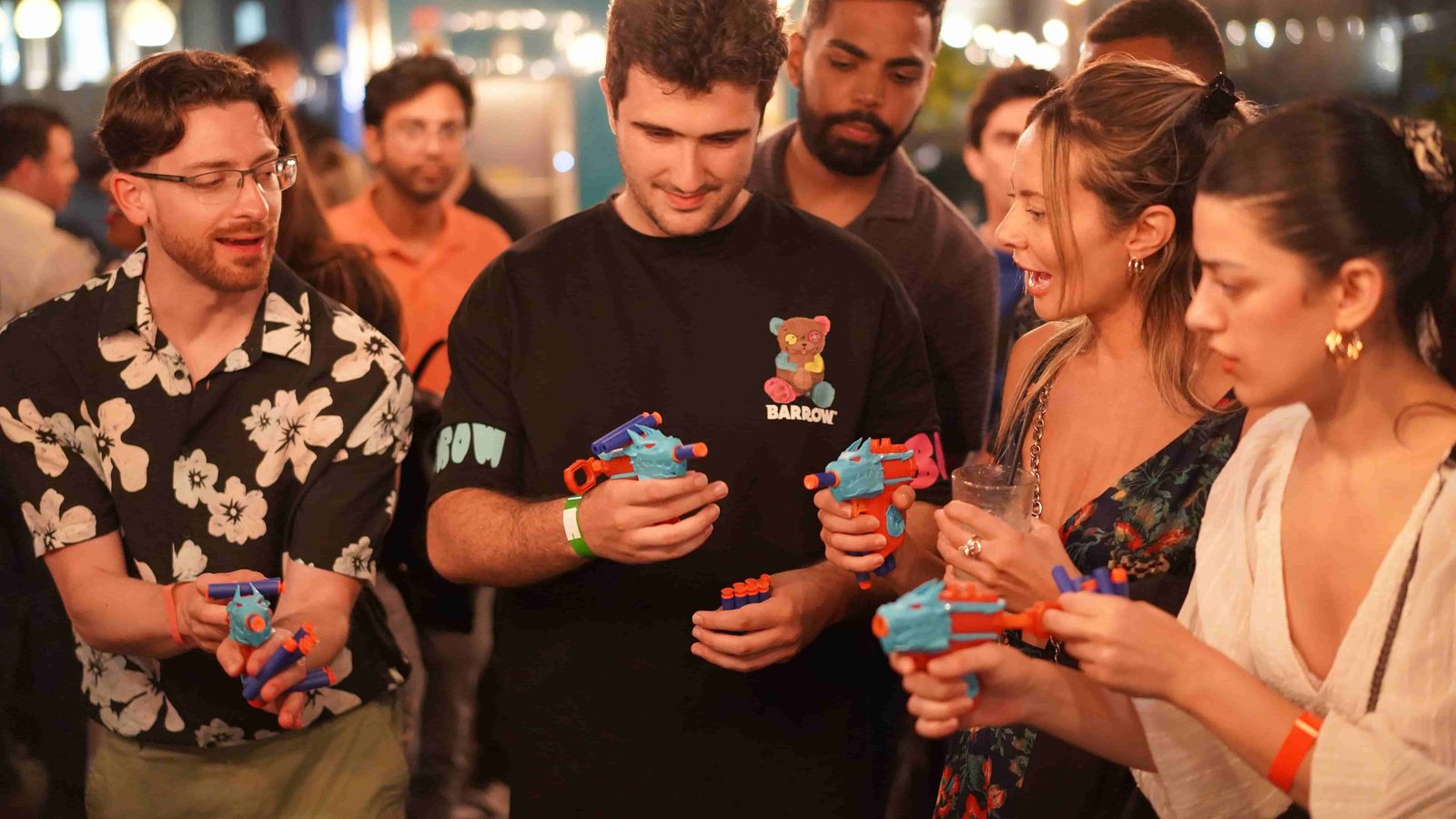 Guests trying toy foam dart blasters together during a Balancers opening social game