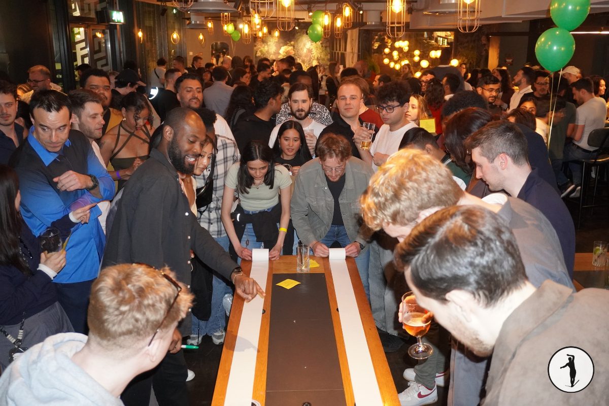 Guests around a long table racing paper strips during a Balancers opening game